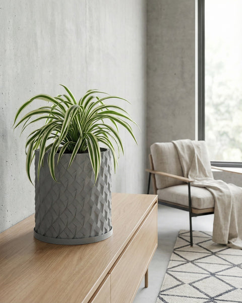 A gray planter pot with a green plant on a wooden table, with a round mirror in the background.
