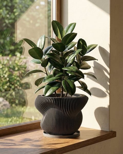 A black, round planter pot with vertical lines sits on a wooden side table next to a gray couch with books and a blanket.