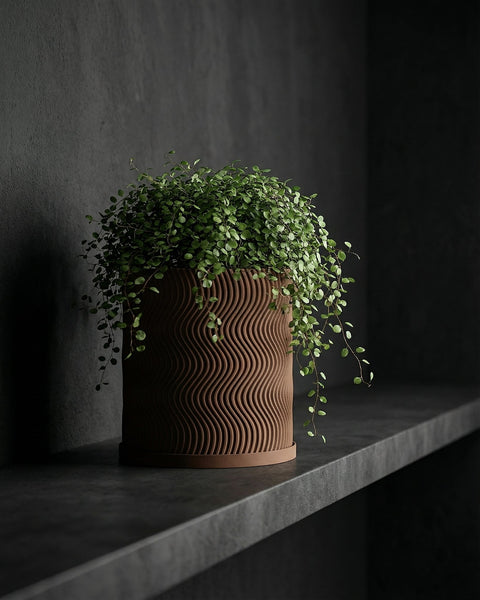 A brown, wavy-textured planter pot with a lush green plant cascading over its edges, displayed on a dark shelf against a dark wall.