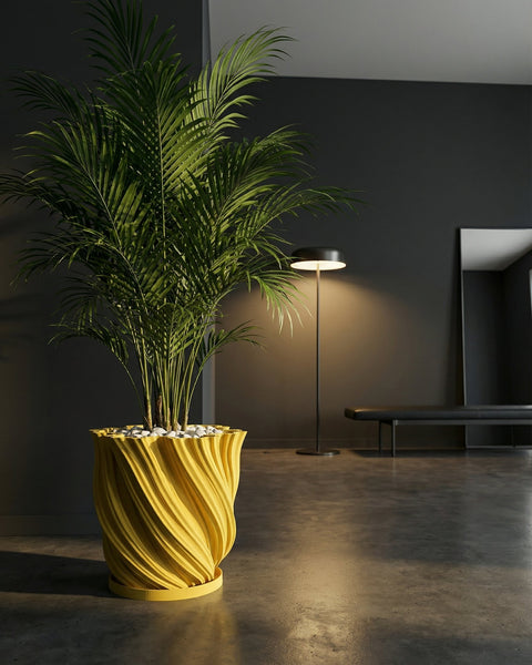 A yellow planter pot with a trailing plant sits on a wooden table next to a gray sofa. The pot has a textured, swirling design.