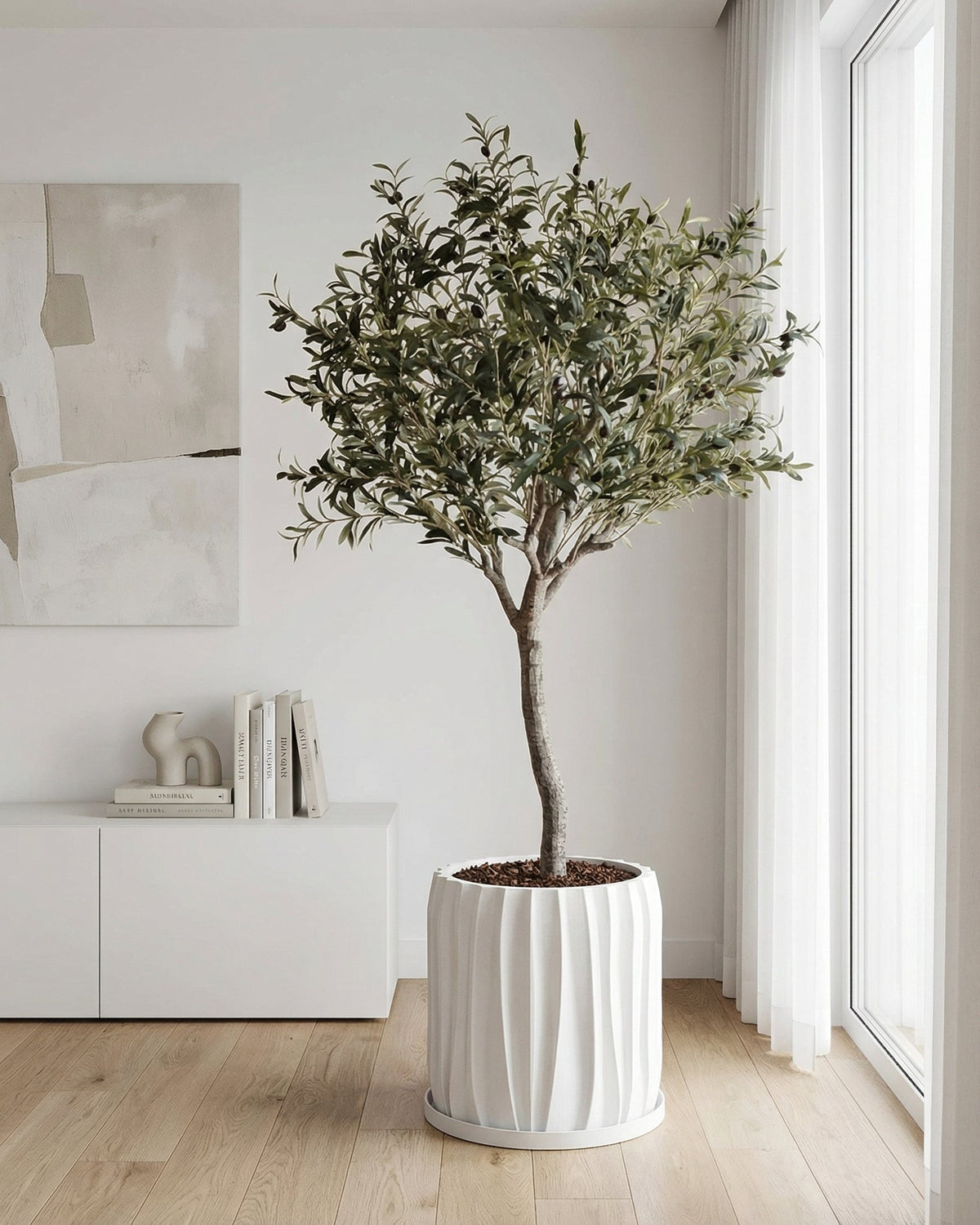 A Pilea peperomioides plant sits in a white, textured planter on a dark wooden side table next to a gray couch.