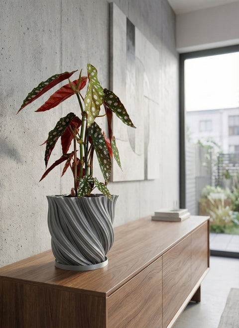 A gray, textured planter pot with a peace lily sits on a wooden console table in a modern entryway with a round mirror.