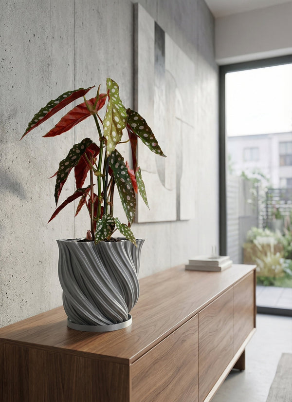 A gray, textured planter pot with a peace lily sits on a wooden console table in a modern entryway with a round mirror.