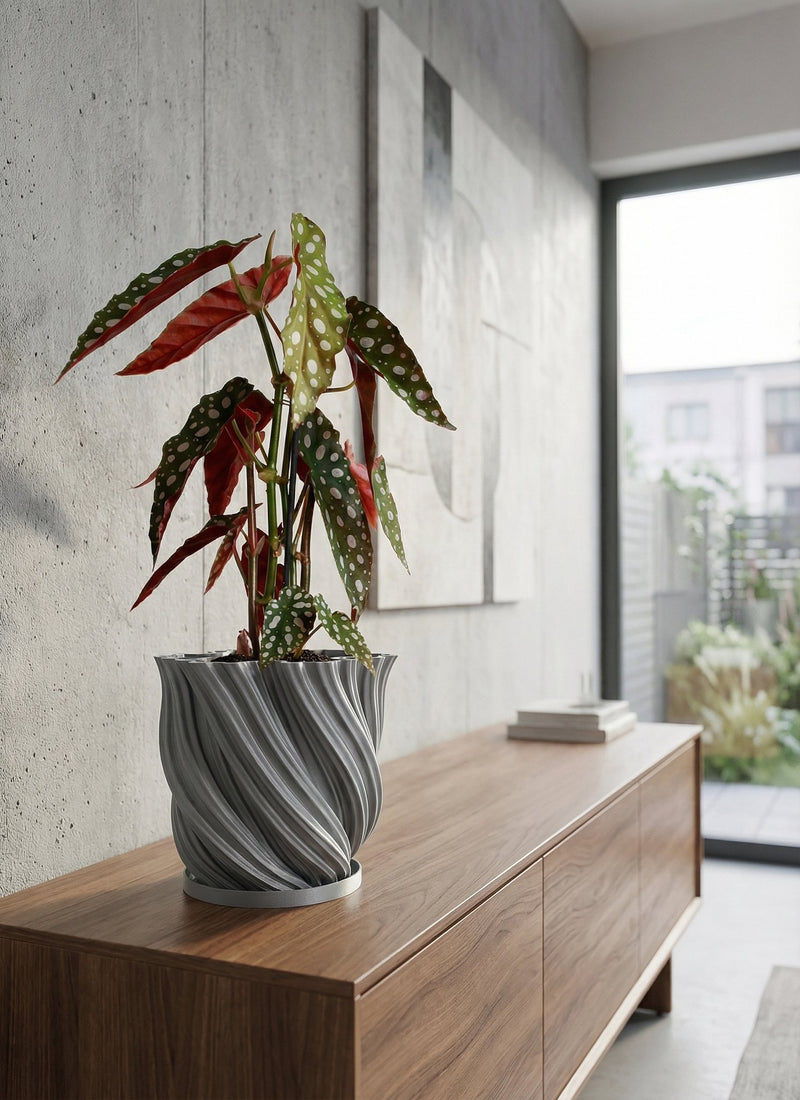 A gray, textured planter pot with a peace lily sits on a wooden console table in a modern entryway with a round mirror.