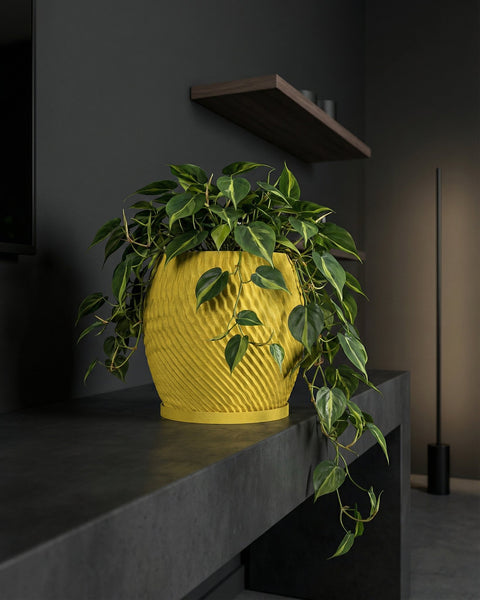 A vibrant yellow planter pot with a lush green plant sits atop a dark gray surface, adding a pop of color to the modern interior.