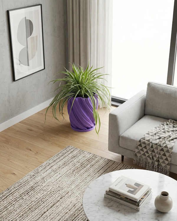 A spider plant in a purple planter pot sits on a dark wood table next to a gray sofa.