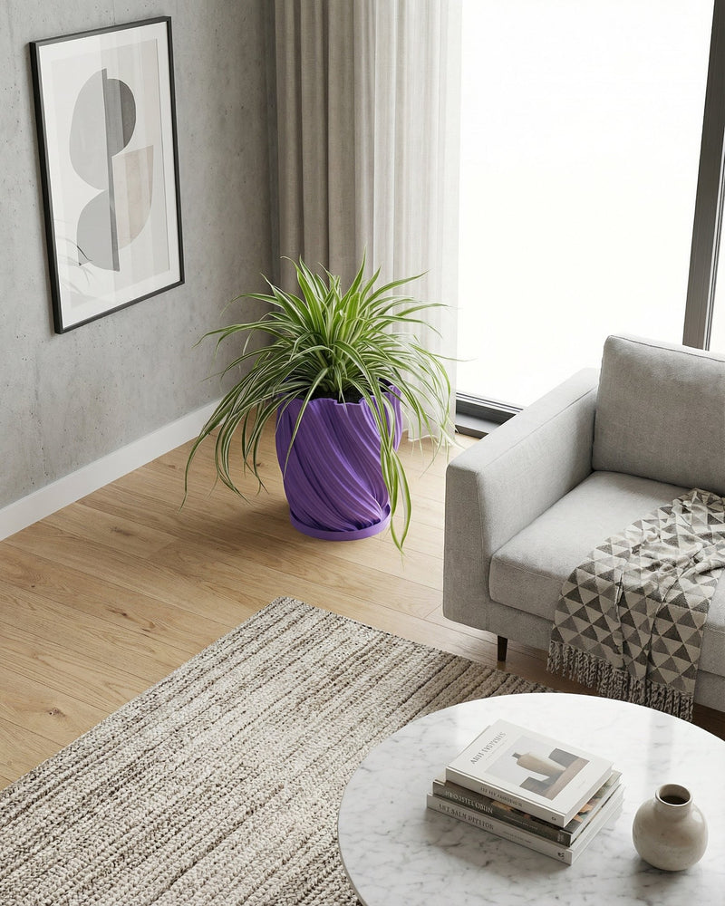 A spider plant in a purple planter pot sits on a dark wood table next to a gray sofa.