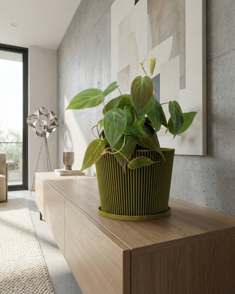 A vibrant pothos plant cascades from a yellow geometric planter atop a wooden cabinet, next to a stack of books and a golden geometric sculpture.