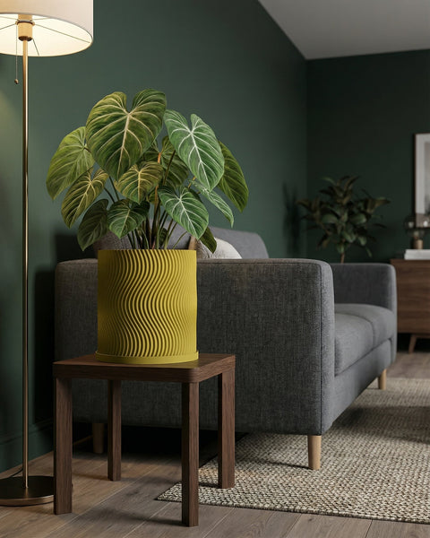 A vibrant green plant in a yellow, wavy-patterned planter pot sits on a wooden side table next to a gray sofa in a cozy living room.