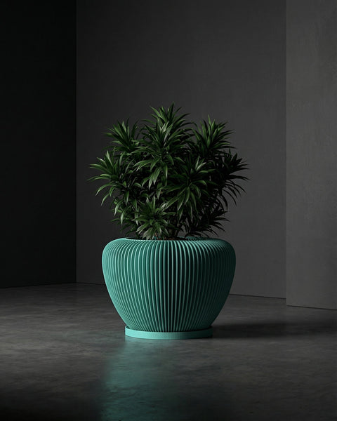 A green planter pot with a plant inside sits on a gray floor in front of a dark gray wall.