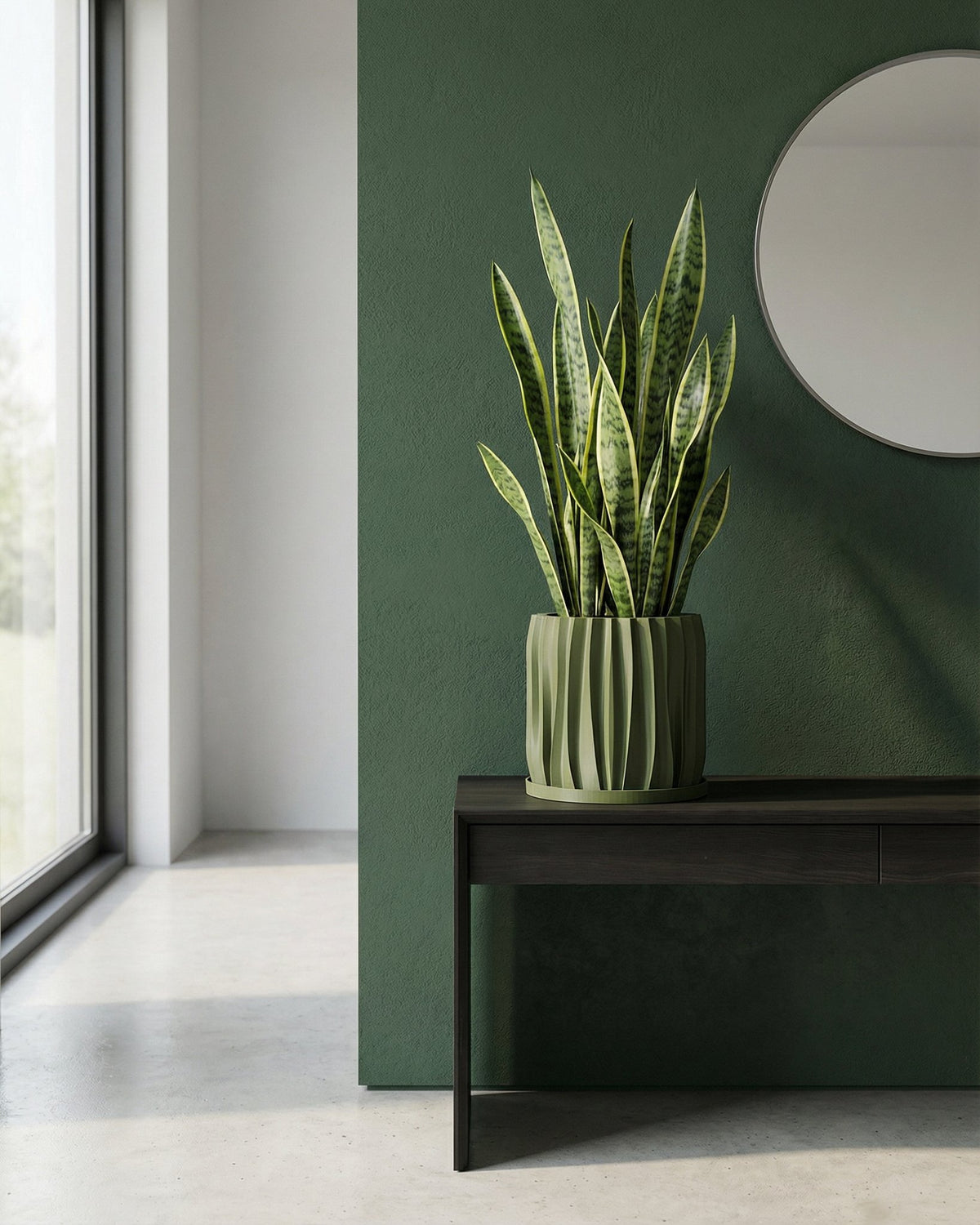 A green planter pot with a plant next to a gray chair in a room with green walls.