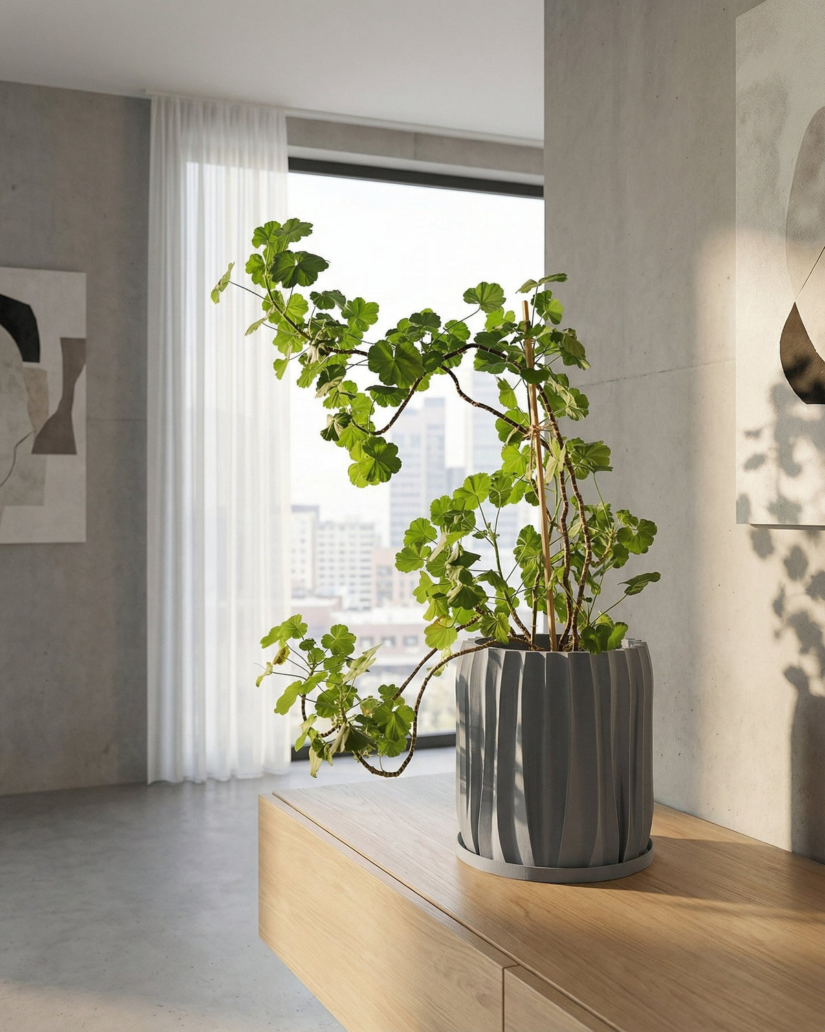 A gray, textured planter pot with a peace lily sits on a wooden console table in a modern entryway with a round mirror.