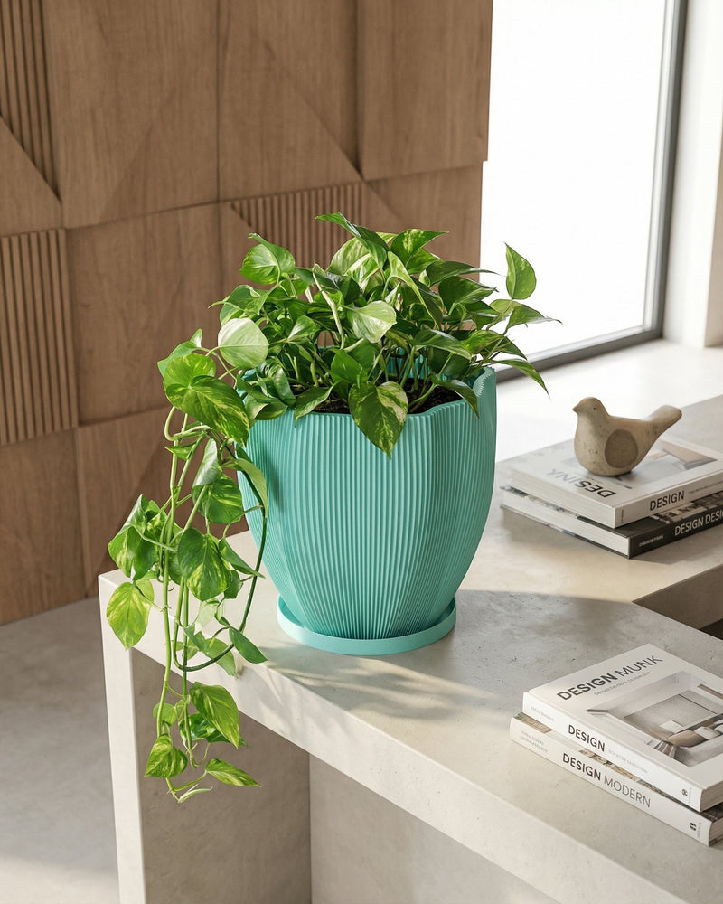 A light blue planter with a plant sits on a wooden windowsill in front of a window.