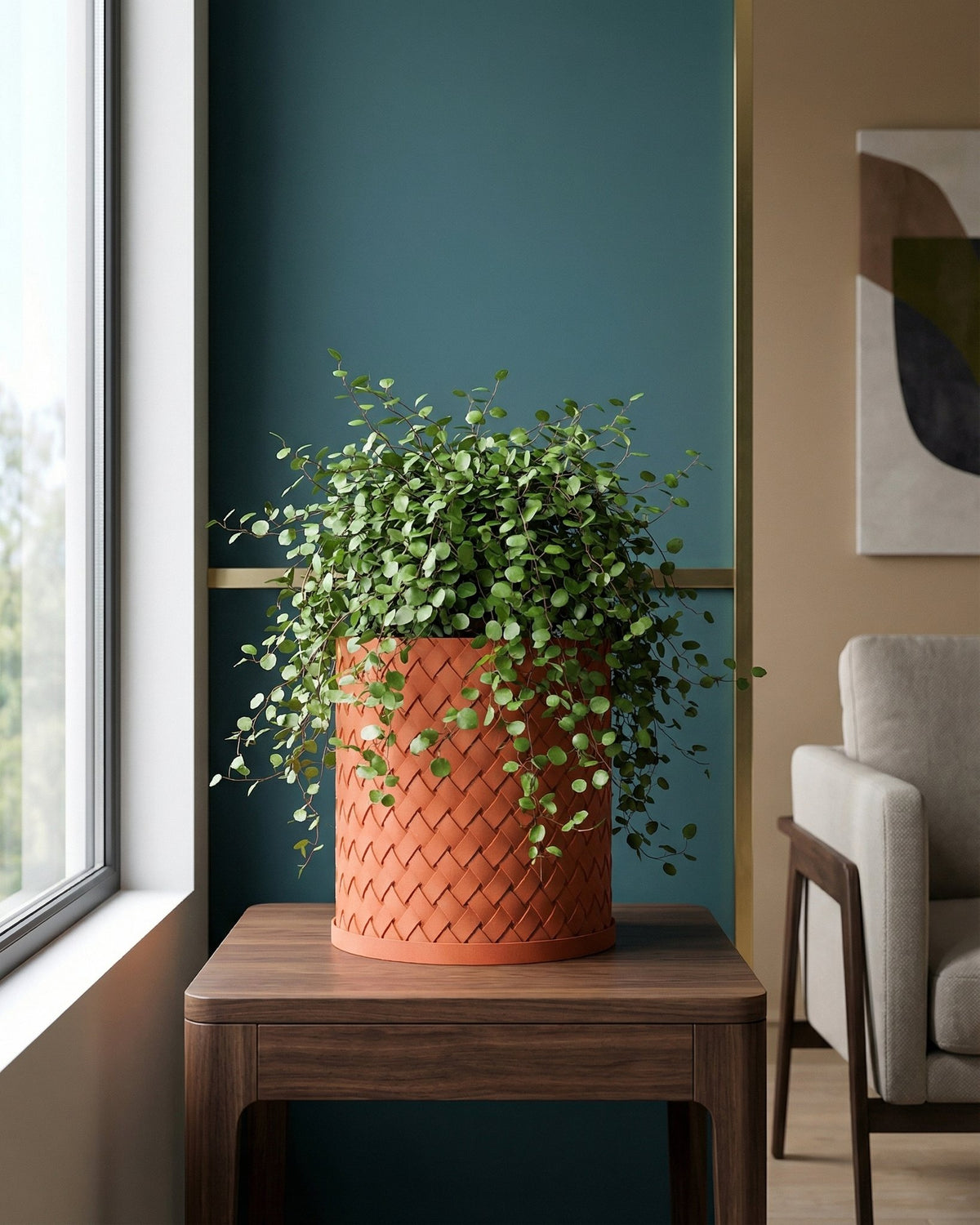 A woven orange planter pot sits on a wooden table next to a window, filled with a lush green plant.