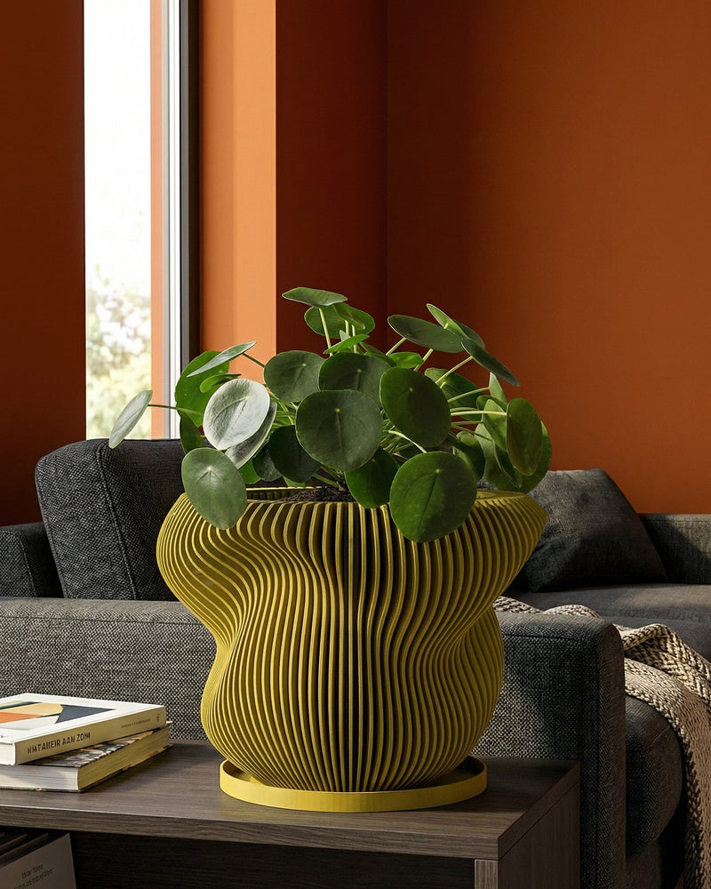 A green planter pot with a bonsai tree sits on a wooden table next to a gray couch in a living room.