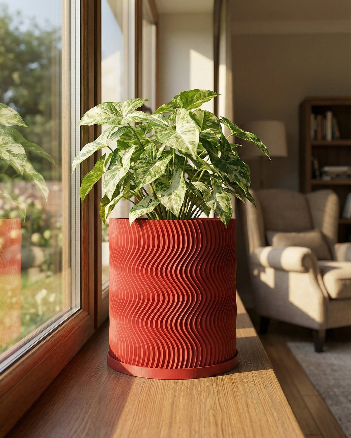A red planter pot with a wavy design sits on a wooden windowsill, holding a lush green plant with white variegation.