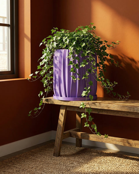 A spider plant in a purple planter pot sits on a dark wood table next to a gray sofa.