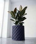 A navy blue planter pot with a green plant on a wooden table with green legs.