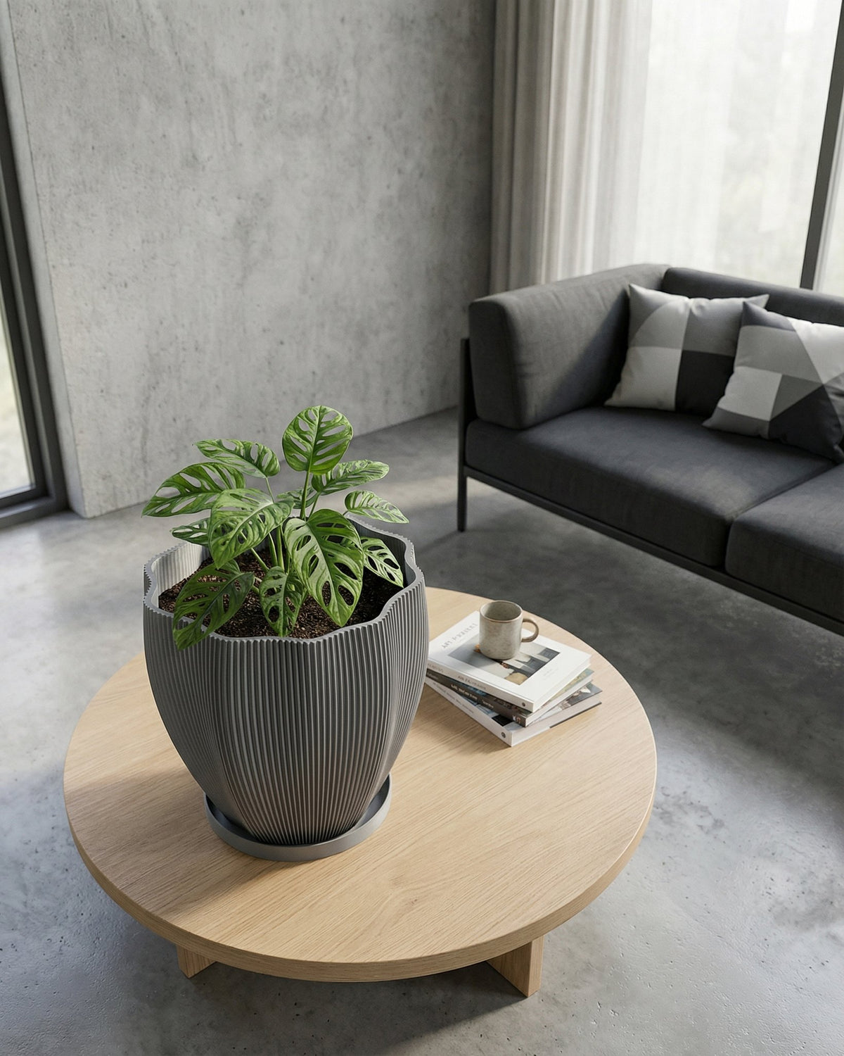 A gray, textured planter pot with a peace lily sits on a wooden console table in a modern entryway with a round mirror.