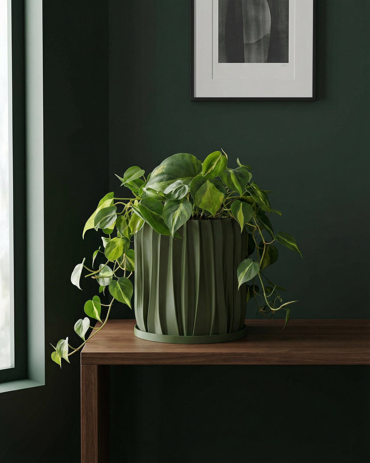 A green planter pot with a houseplant sitting on a windowsill.