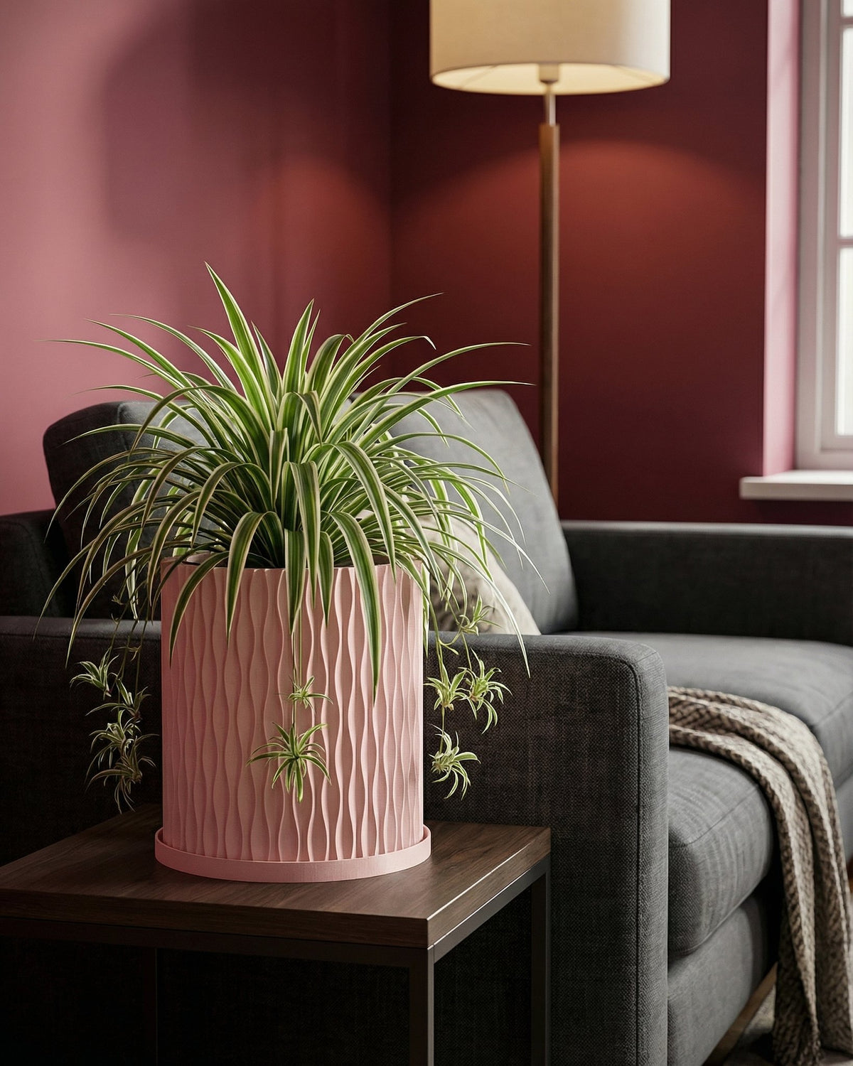 A pink planter pot with a green plant sits on a white windowsill, bathed in sunlight. The pot has a textured, woven design.