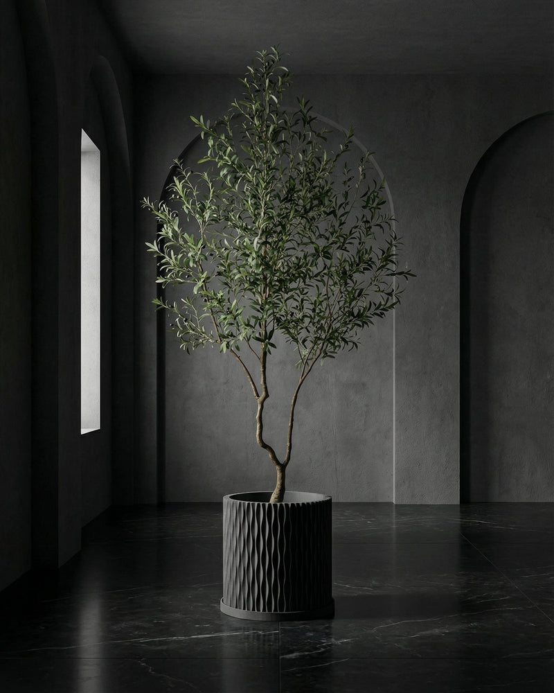 A gray, textured planter pot with a peace lily sits on a wooden console table in a modern entryway with a round mirror.