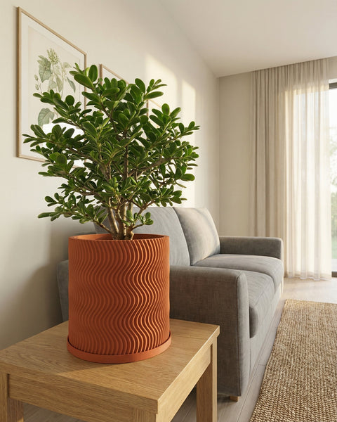 A planter pot with a wavy design sits on a wooden table next to a gray couch in a living room. The pot holds a lush green plant.