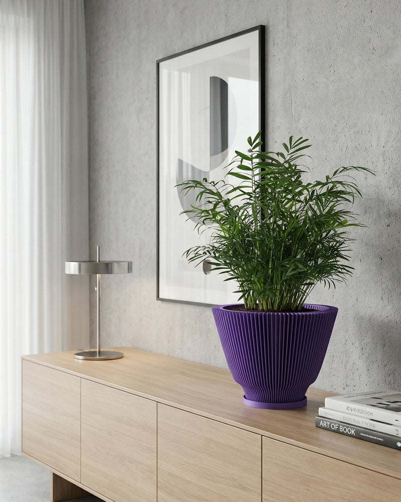 A vibrant purple planter pot sits atop a light wood cabinet, showcasing a lush green plant. A modern lamp and framed artwork add to the stylish interior. The planter's unique ribbed design complements the room's contemporary aesthetic.