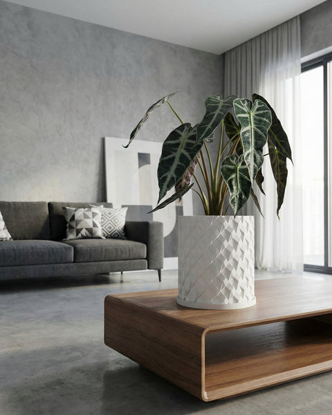 A peace lily in a white textured planter pot sits on a wooden windowsill next to a window.