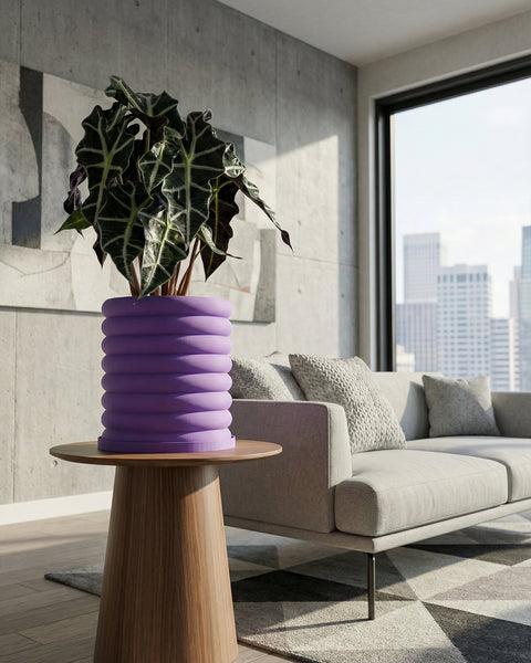 A purple planter pot with a plant on a wooden table in a living room with a couch and a city view.