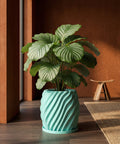 A vibrant green plant sits in a light blue, swirled planter pot on a dark wood floor, adding a pop of color to the room.