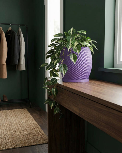 A purple planter pot with a plant on a wooden table. The pot has a textured design.