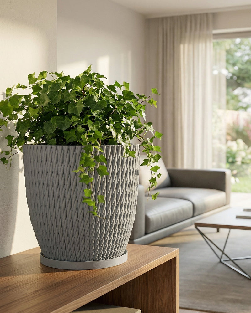 A gray planter pot with a green ivy plant sits on a wooden table in a living room setting.