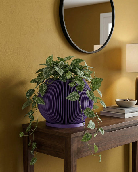 A vibrant purple planter pot sits atop a light wood cabinet, showcasing a lush green plant. A modern lamp and framed artwork add to the stylish interior. The planter's unique ribbed design complements the room's contemporary aesthetic.