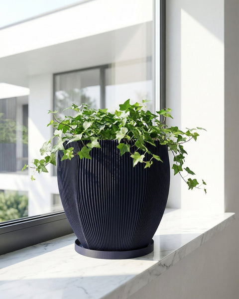A blue planter pot with a textured design sits on a wooden bench, filled with a lush green plant with unique leaf shapes.