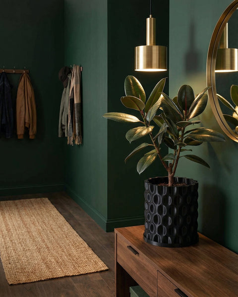 A black planter pot with a textured, bubble-like pattern sits on a wooden console table in a stylish entryway with dark green walls.