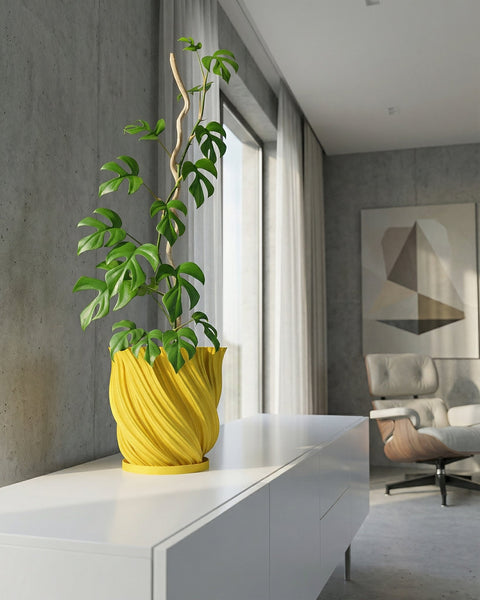 A Monstera plant with variegated leaves in a yellow textured planter pot sits on a jute rug.