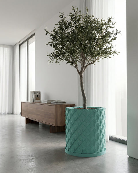 A turquoise planter pot with a plant sits on a wooden cabinet in a blue-themed room with a round mirror.