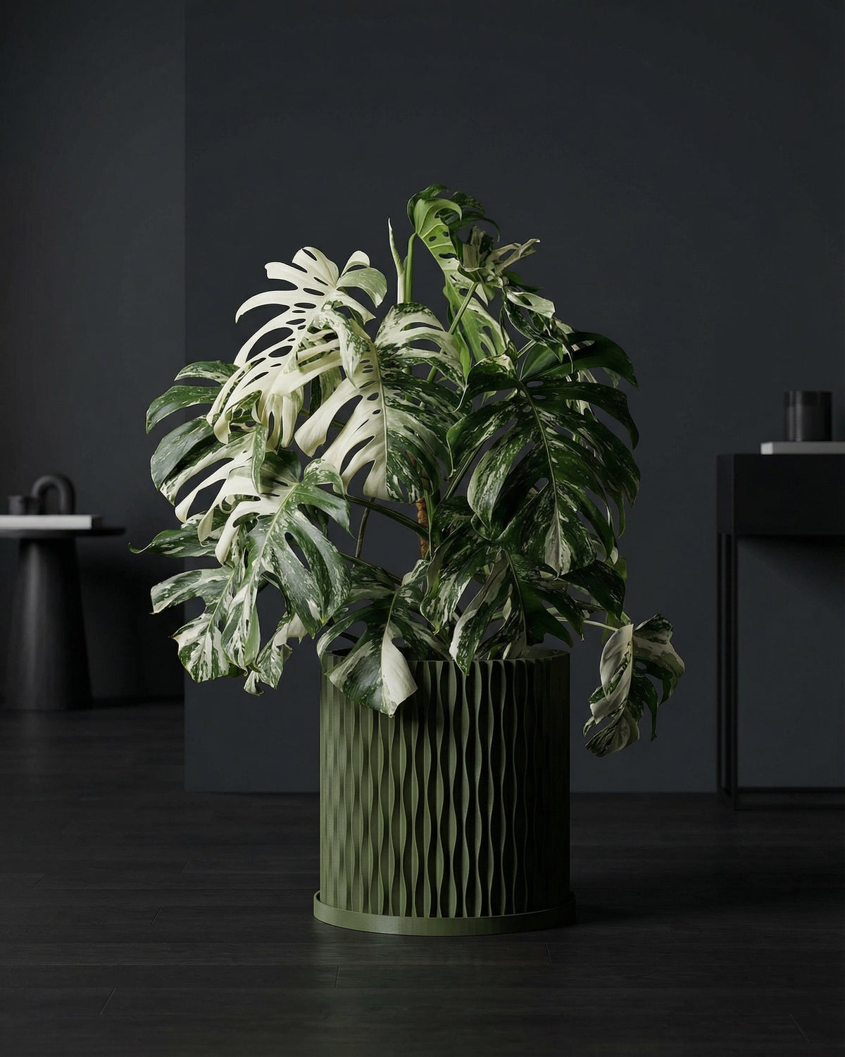 A green planter pot with a plant next to a gray chair in a room with green walls.
