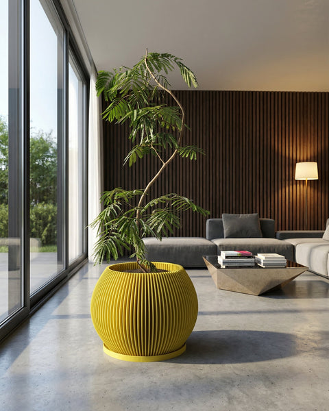 A vibrant yellow planter pot with a green plant inside sits in a modern living room with large windows and a sleek design.