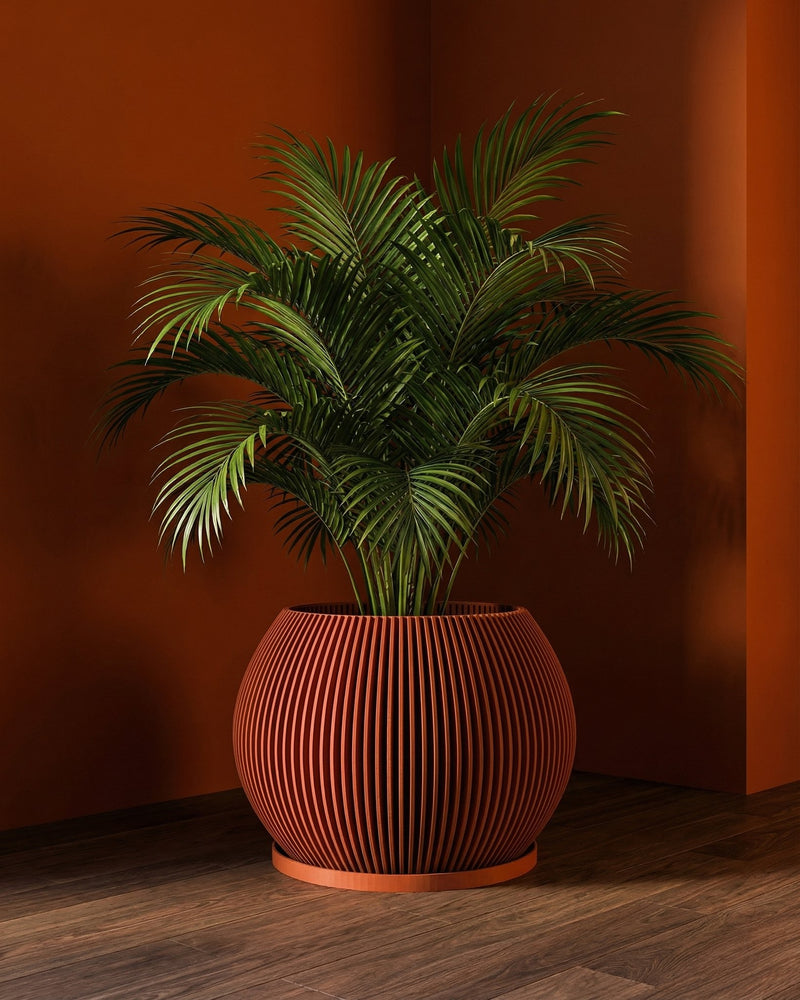 A vibrant green palm plant sits in a modern, orange-toned, vertically-striped planter pot on a wooden floor against a matching orange wall.