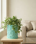 A vibrant green ivy cascades from a textured turquoise planter pot, adding a touch of nature to a cozy living space.