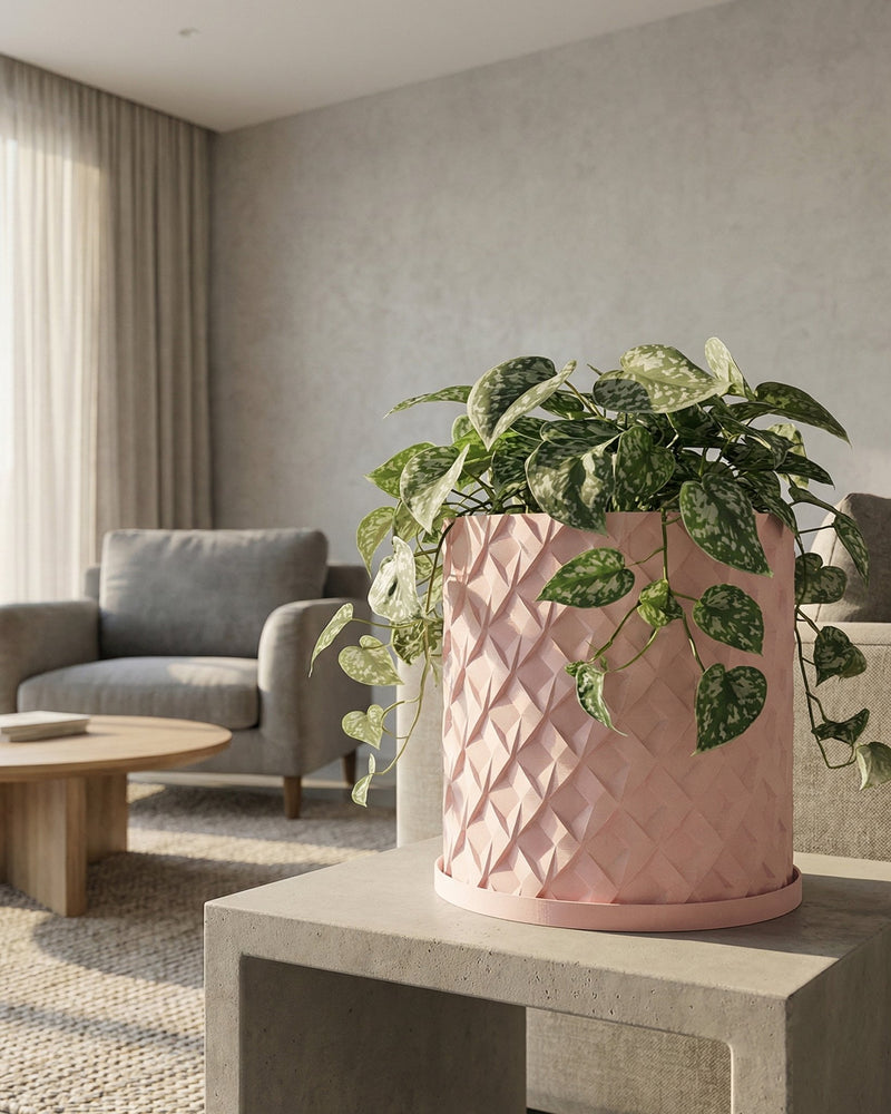A pink planter pot with a plant inside sits on a dark wood cabinet with books and vases.