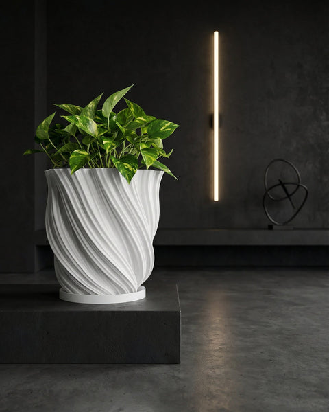 A white planter pot with a polka dot plant sits on a round concrete table. A rug and bench are in the background.