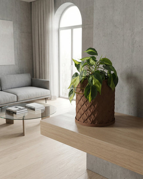 A brown planter pot with a green plant inside sits on a wooden table in a room with blue walls and a round mirror.