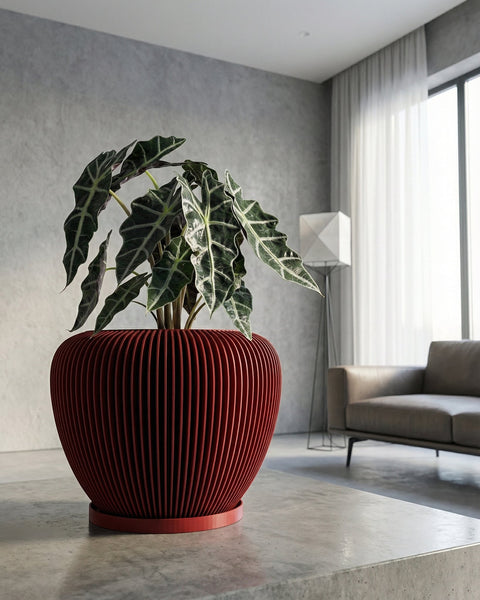 A red planter pot with a plant inside sits on a concrete surface in a modern room. The pot has a ribbed design.