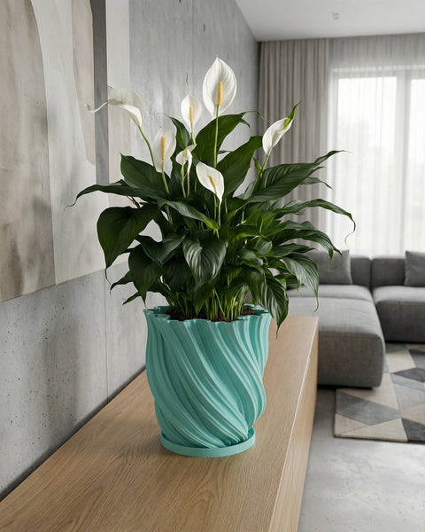 A light blue planter with a plant sits on a wooden windowsill in front of a window.