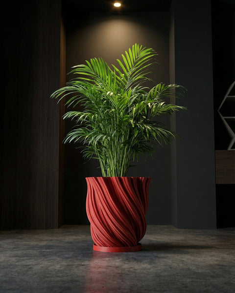 A red planter pot with a plant sits on a dark wooden bench in a room with dark green walls and a round gold mirror.