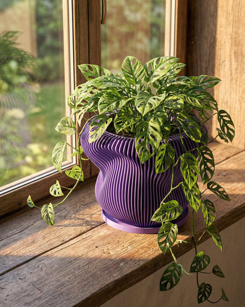 A purple planter pot with a green plant sits on a white windowsill next to a window.