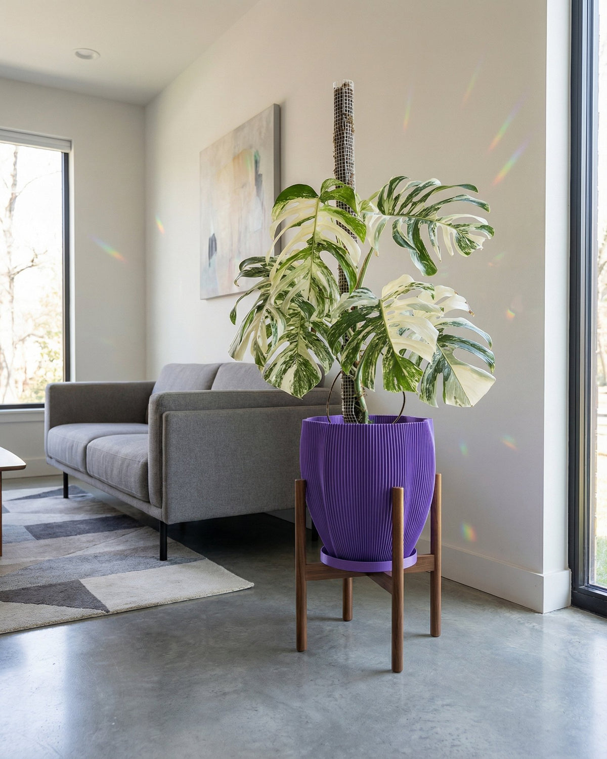 A purple planter pot with a green plant inside sitting on a window sill.
